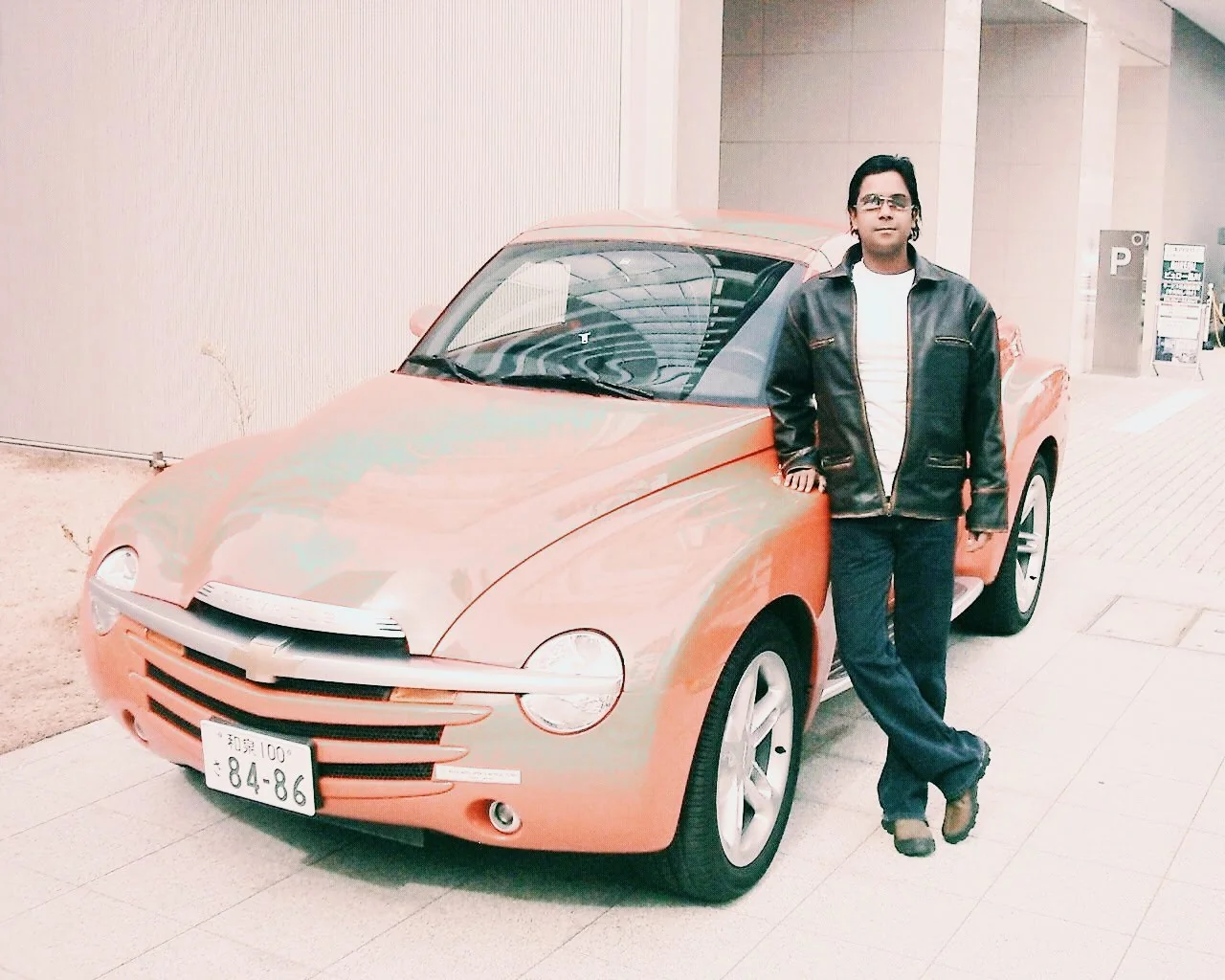 Dholi Baba leaning beside a bright sports car