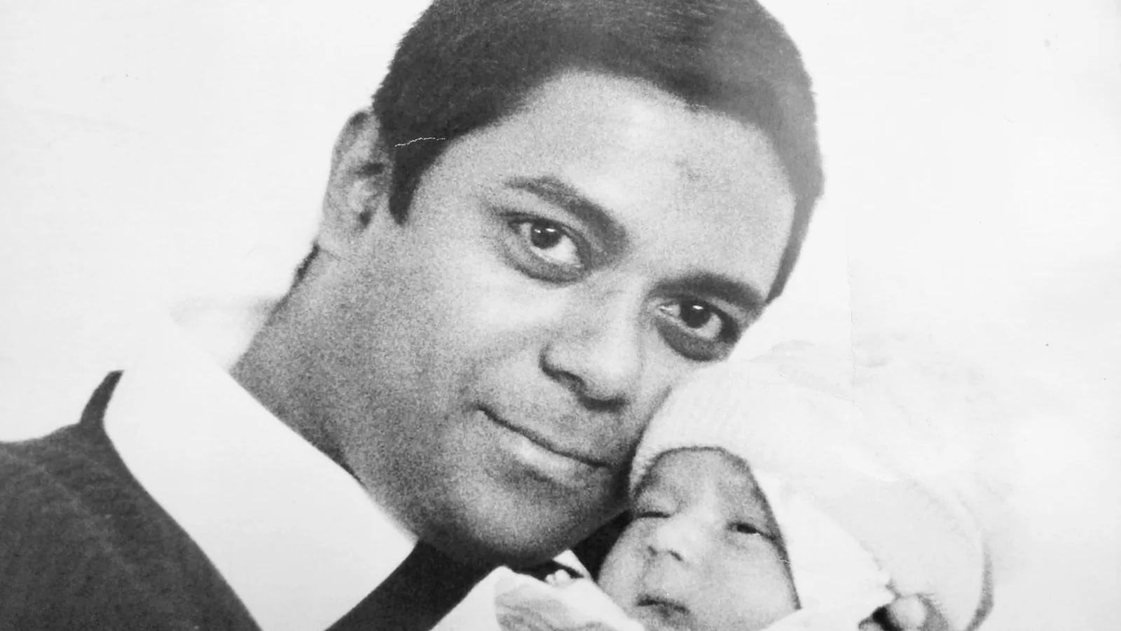 Dholi Baba holding his newborn child in a black-and-white photograph